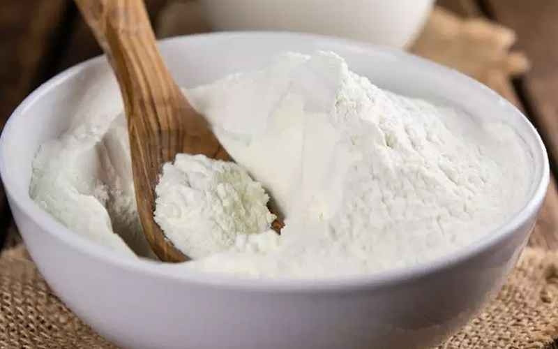 Bột kem béo trắng mịn trên thìa, sẵn sàng pha chế