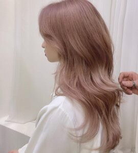 Hình ảnh cô gái với mái tóc nâu trà sữa ánh tím nổi bật, gương mặt rạng rỡ và phong cách ấn tượng