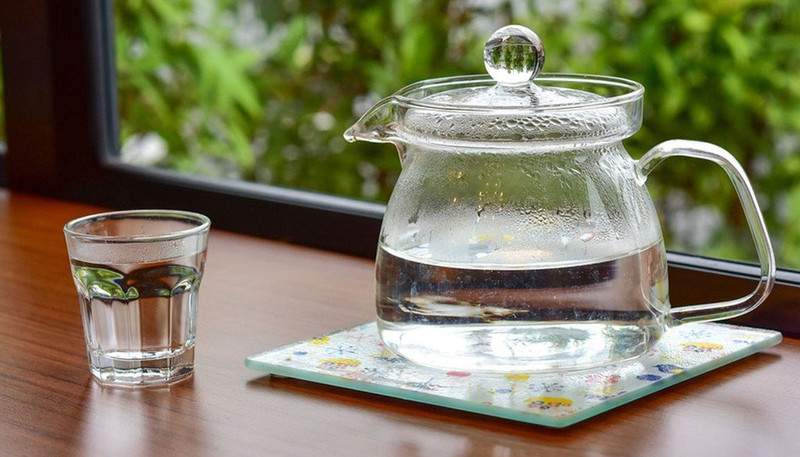 Một cốc nước ấm với lát chanh và lá bạc hà, minh họa thức uống tốt giúp làm dịu cơn đau bụng kinh và giảm chuột rút trong kỳ kinh nguyệt.