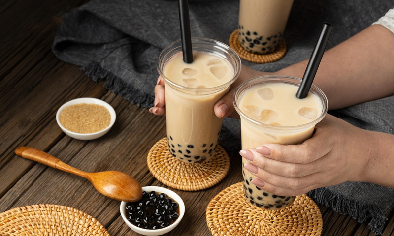 Một cốc trà sữa trân châu đang được thưởng thức, đặt câu hỏi về việc tới tháng uống trà sữa được không và tác động đến chu kỳ kinh nguyệt.