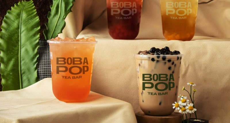 Một ly trà sữa Bobapop với trân châu và thạch, cùng với logo thương hiệu trên ly