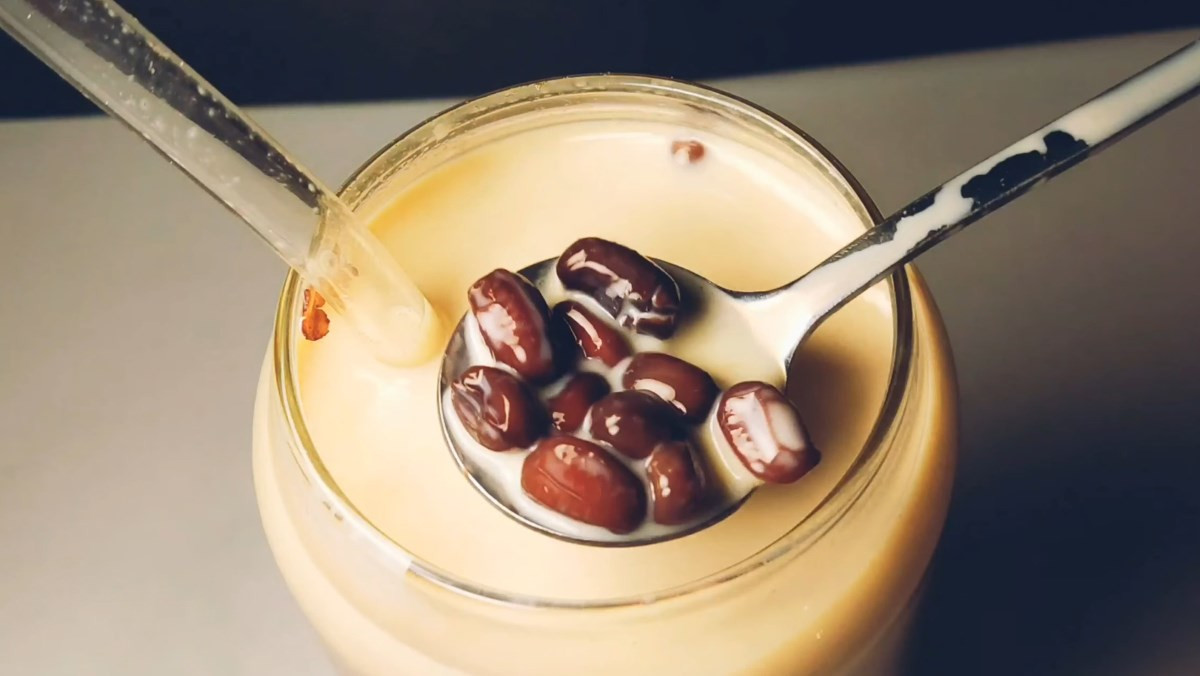 Một ly trà sữa đậu đỏ hấp dẫn với đá và topping đậu đỏ phía trên