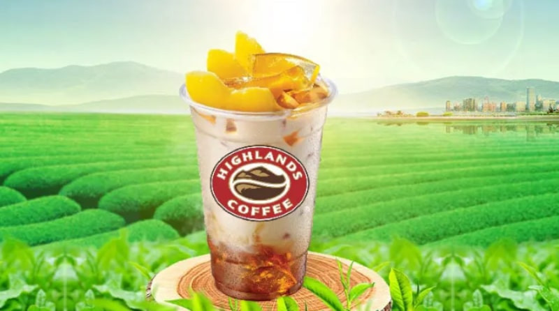 Một ly trà sữa Highland Coffee với topping trân châu và kem sữa, đặt trên bàn cà phê