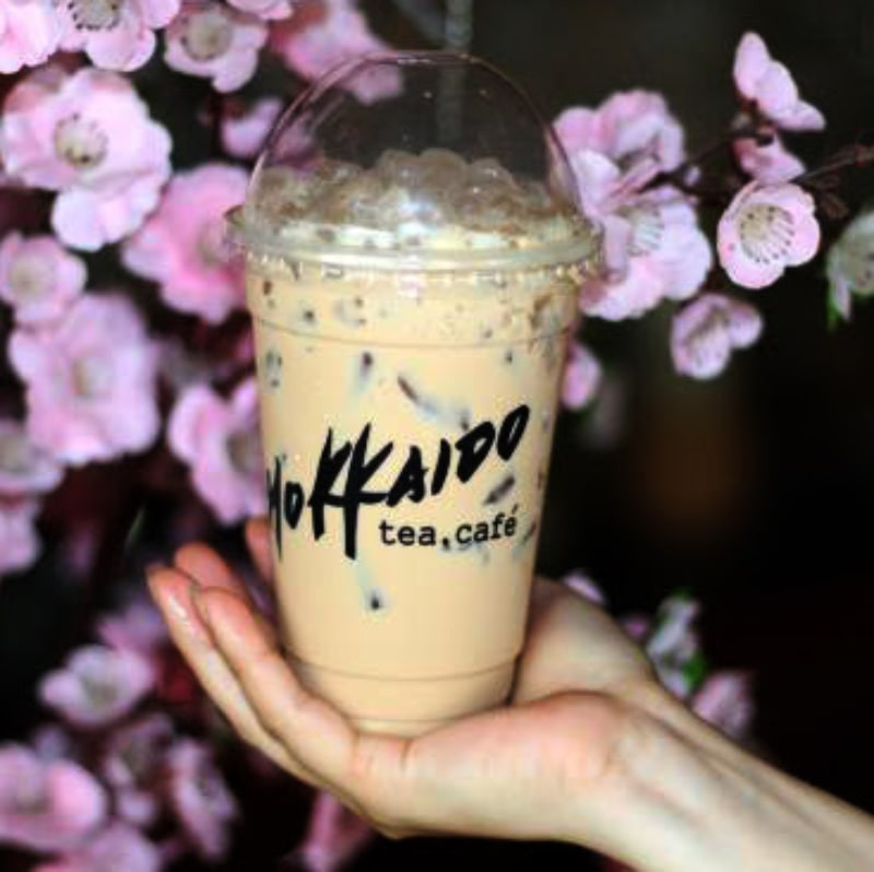 Một ly trà sữa Hokkaido với topping trân châu và thạch, đặt trên bàn gỗ màu sáng