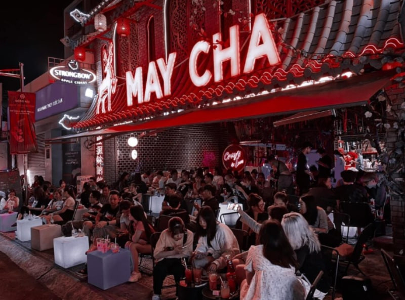 Một ly trà sữa Maycha màu xanh lá, kèm trân châu đen và một chiếc lá bạc hà trang trí trên bàn gỗ