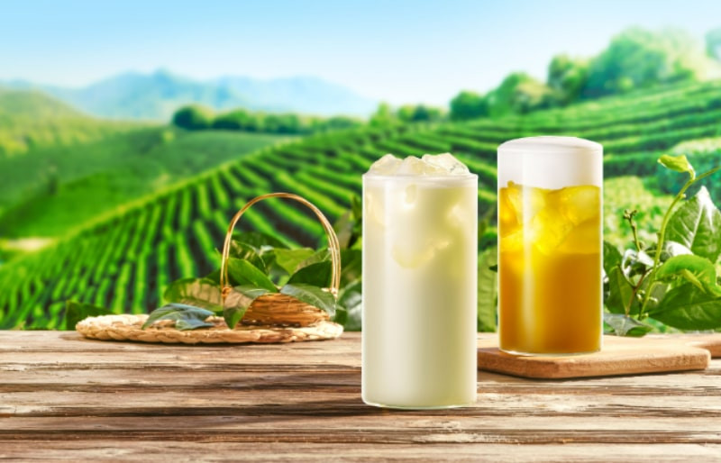 Một ly trà sữa Phúc Long với đá và lớp kem cheese dày bên trên, đặt trên một chiếc đĩa trắng